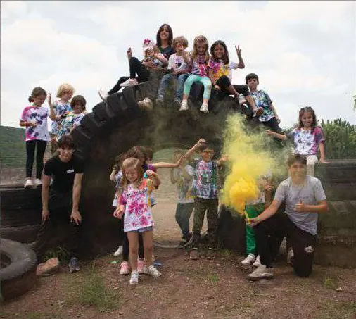 Niños y adultos posando en un arco de llantas, con polvo amarillo.