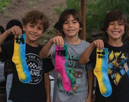 Tres niños mostrando calcetines de colores.