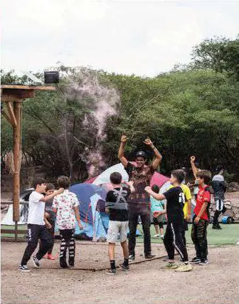 Grupo de niños y un adulto con humo de color, en un claro del parque.