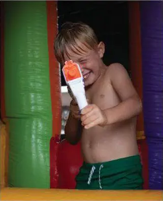 Niño dentro de un inflable de colores, con un juguete de agua.
