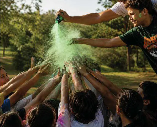 Personas en círculo, con las manos al centro, mientras alguien esparce polvo verde.